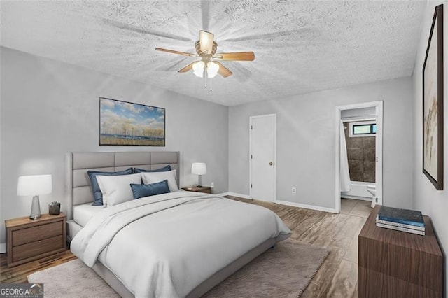 bedroom with ceiling fan, connected bathroom, a textured ceiling, and light wood-type flooring