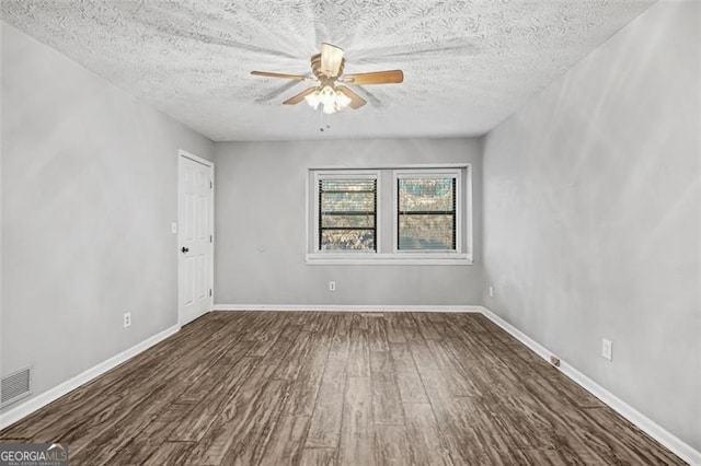 empty room featuring dark wood-type flooring, ceiling fan, and a textured ceiling