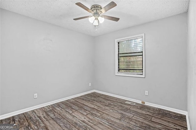 empty room featuring dark wood-type flooring, ceiling fan, and a textured ceiling