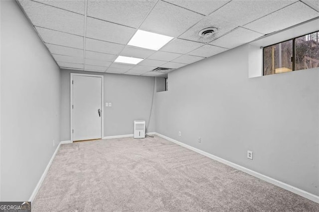 basement featuring light colored carpet and a drop ceiling