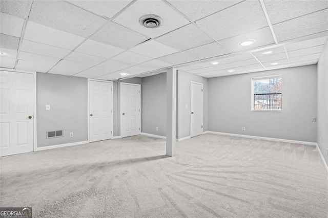 basement featuring a drop ceiling and light colored carpet