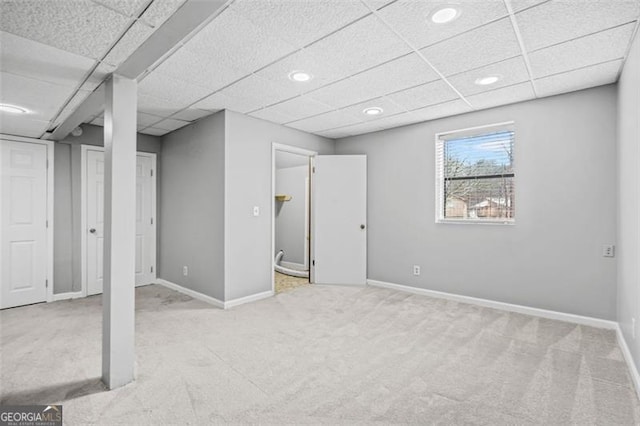 basement featuring a drop ceiling and light colored carpet