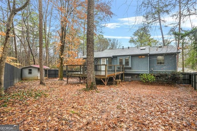 back of house featuring cooling unit, a wooden deck, and a storage shed