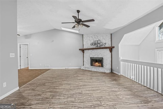 unfurnished living room featuring a fireplace, wood-type flooring, lofted ceiling, ceiling fan, and a textured ceiling