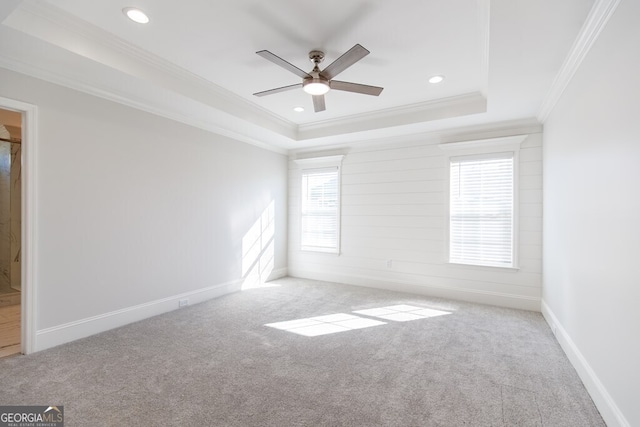 unfurnished room featuring ceiling fan, light colored carpet, ornamental molding, and a tray ceiling