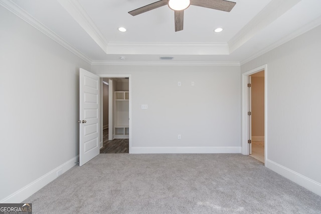 unfurnished bedroom featuring crown molding, a raised ceiling, and carpet floors