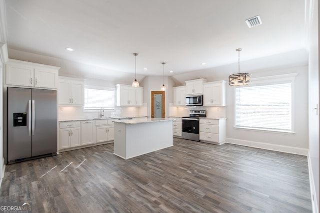 kitchen featuring pendant lighting, appliances with stainless steel finishes, white cabinetry, a kitchen island, and decorative backsplash