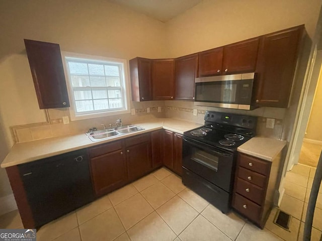 kitchen with backsplash, light tile patterned floors, sink, and black appliances