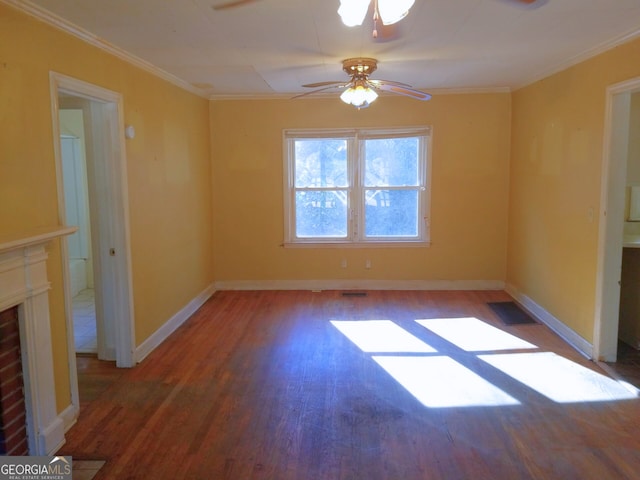 spare room featuring crown molding, ceiling fan, a fireplace, and dark hardwood / wood-style flooring