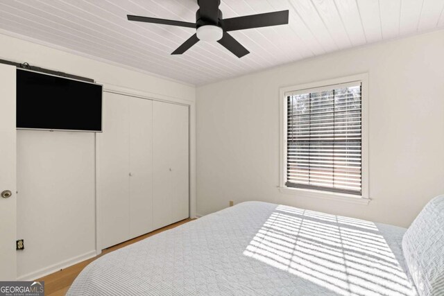 bedroom with wood-type flooring, wooden ceiling, ceiling fan, and a closet