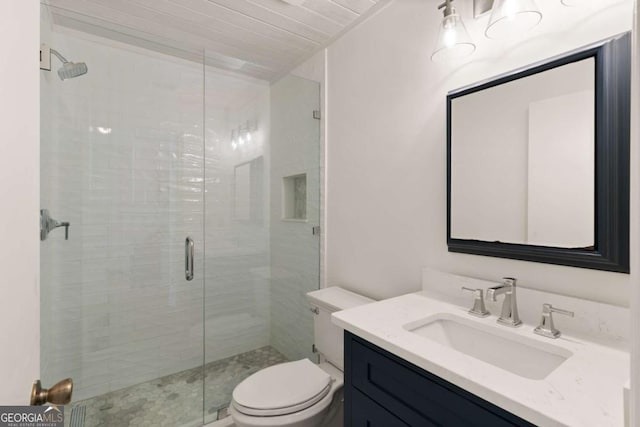 bathroom featuring vanity, a shower with shower door, and toilet