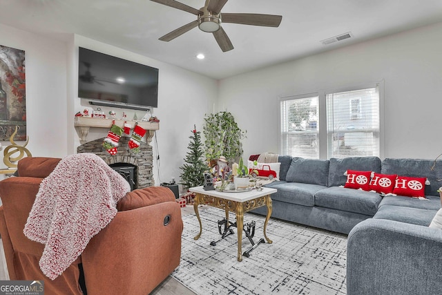 living room featuring ceiling fan, a fireplace, and light wood-type flooring