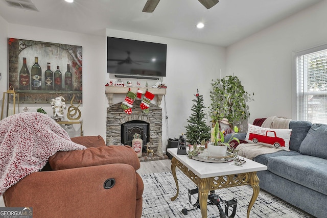 living room with a fireplace, light hardwood / wood-style flooring, and ceiling fan