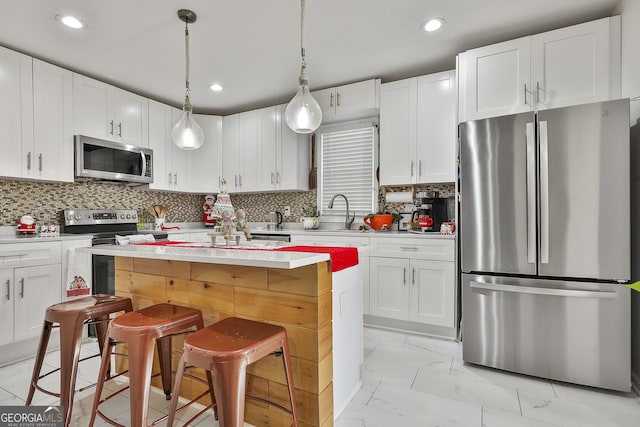 kitchen featuring stainless steel appliances, pendant lighting, white cabinets, and a kitchen bar