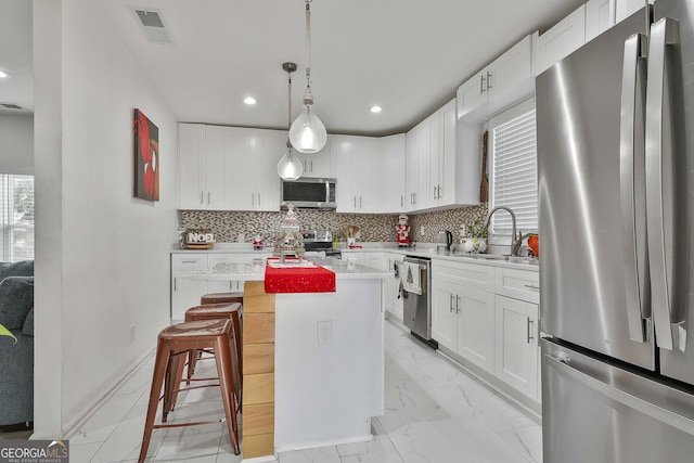 kitchen featuring stainless steel appliances, a center island, sink, and white cabinets