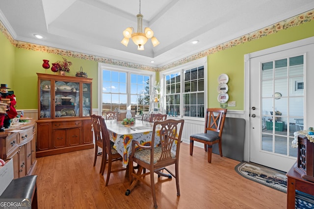 dining room with ornamental molding, light hardwood / wood-style floors, a raised ceiling, and a chandelier