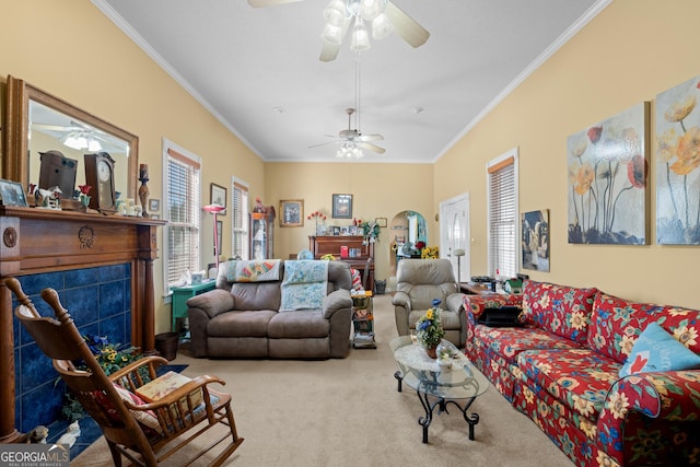 living room with ceiling fan, ornamental molding, carpet flooring, and a tile fireplace