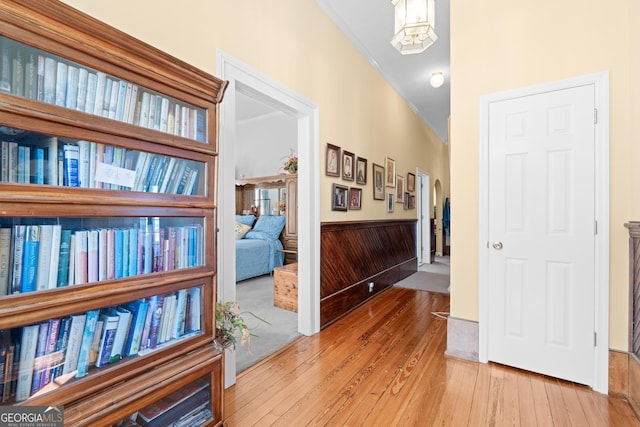 corridor featuring a notable chandelier, hardwood / wood-style flooring, wooden walls, and ornamental molding