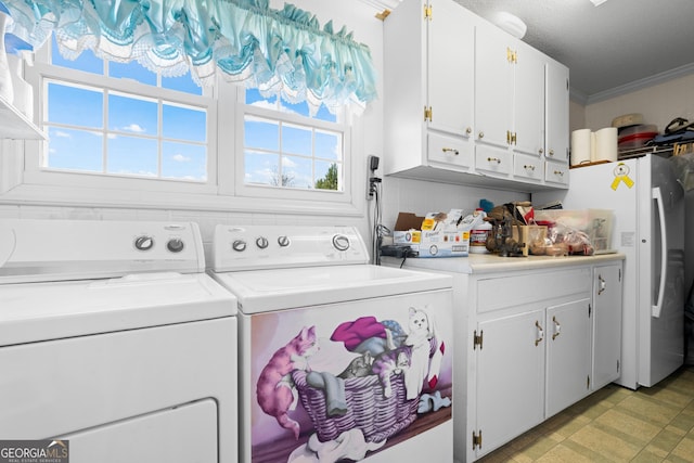 laundry room featuring crown molding, cabinets, and washing machine and clothes dryer