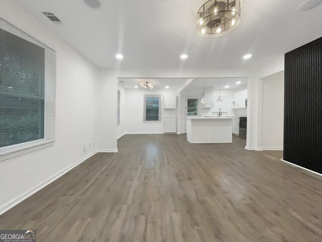 unfurnished living room featuring an inviting chandelier and dark wood-type flooring