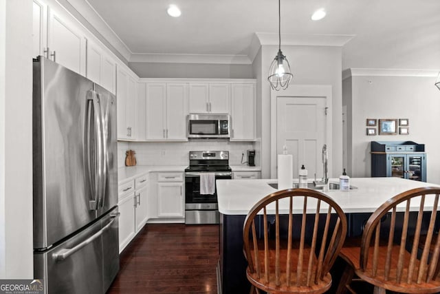 kitchen featuring pendant lighting, crown molding, stainless steel appliances, a center island, and white cabinets