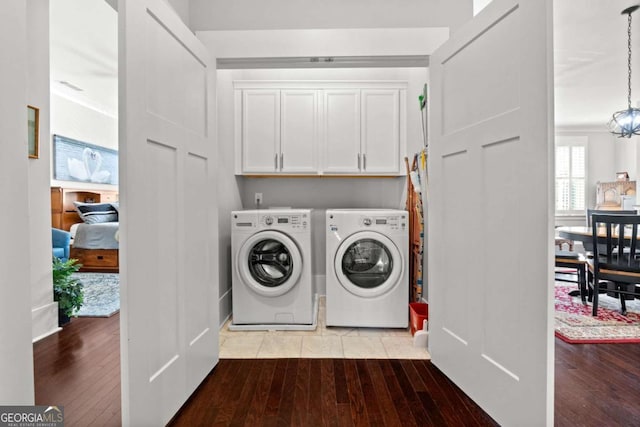 laundry room with cabinets, a notable chandelier, washer and clothes dryer, and light hardwood / wood-style flooring