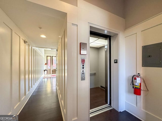 hall featuring dark wood-type flooring, elevator, and electric panel