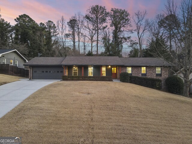 ranch-style home with a garage and a lawn