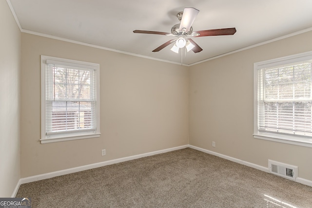 carpeted spare room featuring crown molding, a wealth of natural light, and ceiling fan