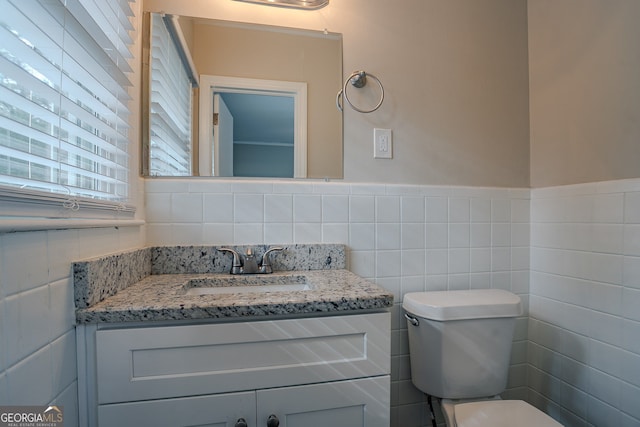 bathroom featuring vanity, toilet, and tile walls