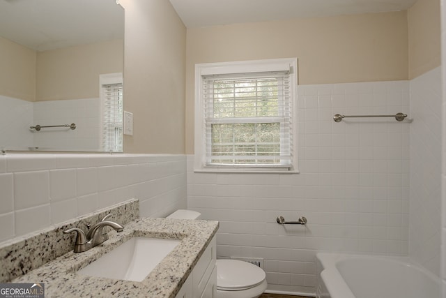 bathroom featuring a tub to relax in, vanity, toilet, and tile walls