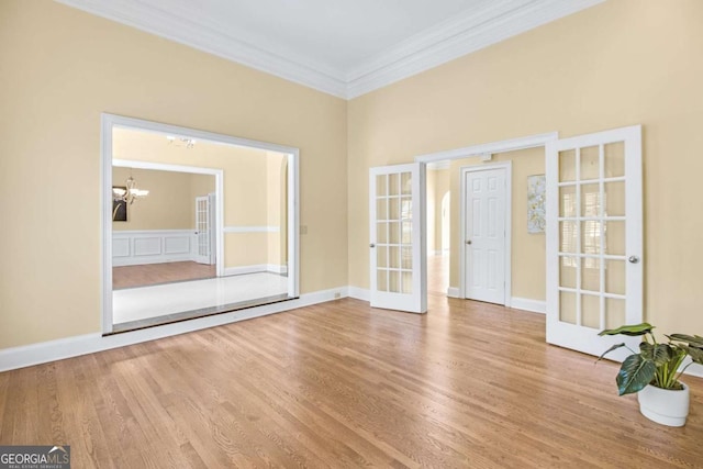 unfurnished room featuring crown molding, a chandelier, light hardwood / wood-style floors, and french doors