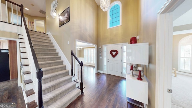 entryway featuring dark wood-type flooring, an inviting chandelier, and a towering ceiling