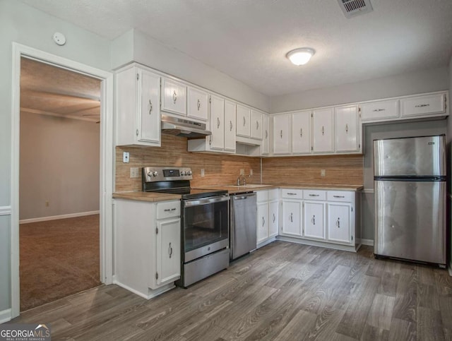 kitchen with backsplash, stainless steel appliances, dark hardwood / wood-style flooring, and white cabinets