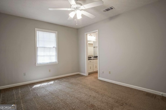 carpeted spare room featuring a textured ceiling and ceiling fan