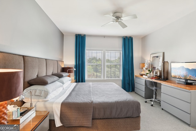 bedroom with built in desk, light colored carpet, and ceiling fan