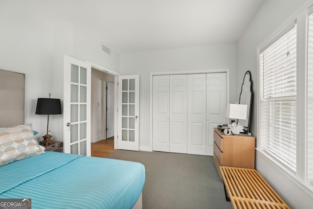 carpeted bedroom featuring french doors, multiple windows, a closet, and visible vents