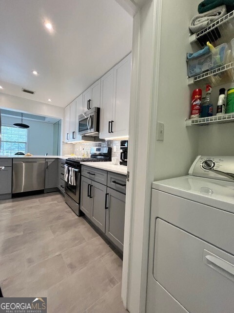 kitchen featuring washer / dryer, white cabinetry, appliances with stainless steel finishes, gray cabinets, and decorative backsplash