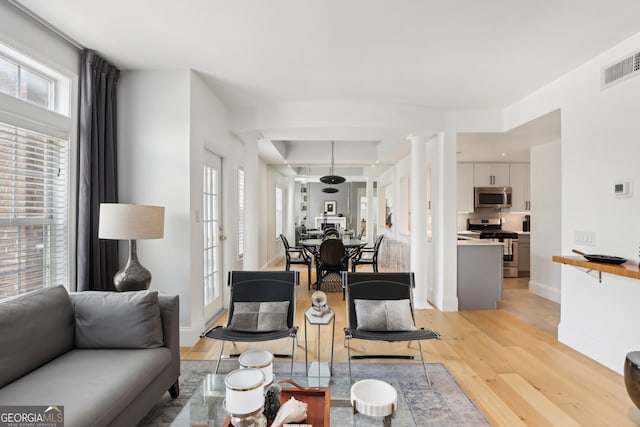 living room with light hardwood / wood-style flooring and ornate columns