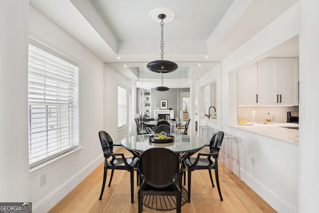 dining space featuring a tray ceiling and light hardwood / wood-style floors