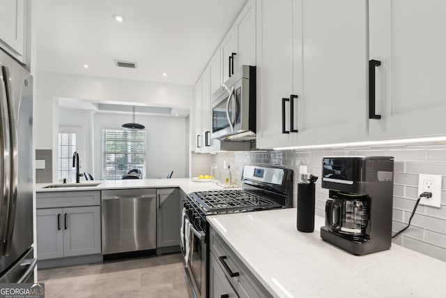 kitchen with appliances with stainless steel finishes, decorative light fixtures, sink, gray cabinetry, and decorative backsplash