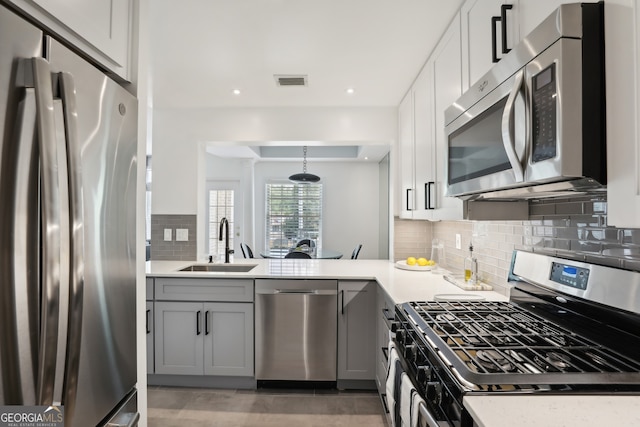 kitchen with appliances with stainless steel finishes, decorative light fixtures, sink, gray cabinetry, and decorative backsplash