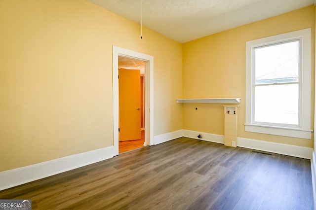 spare room featuring dark hardwood / wood-style floors and a textured ceiling