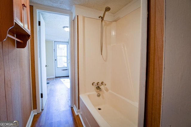 bathroom with wood-type flooring, tub / shower combination, and a textured ceiling