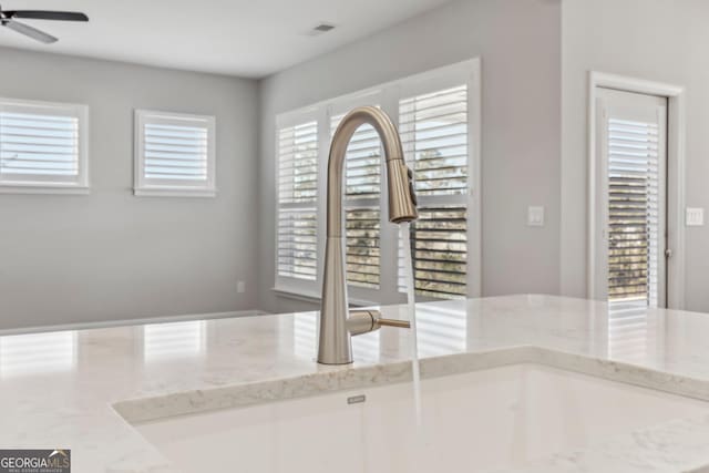 details featuring ceiling fan, sink, and light stone counters