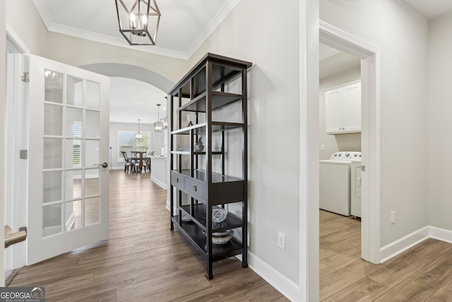 hall featuring ornamental molding, washer and dryer, hardwood / wood-style floors, and an inviting chandelier