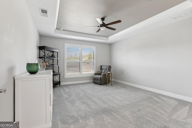 sitting room with light colored carpet, ceiling fan, and a tray ceiling