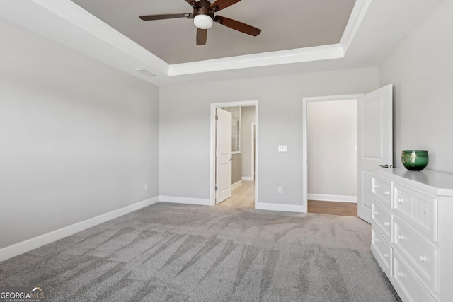 unfurnished bedroom with ceiling fan, light colored carpet, and a tray ceiling