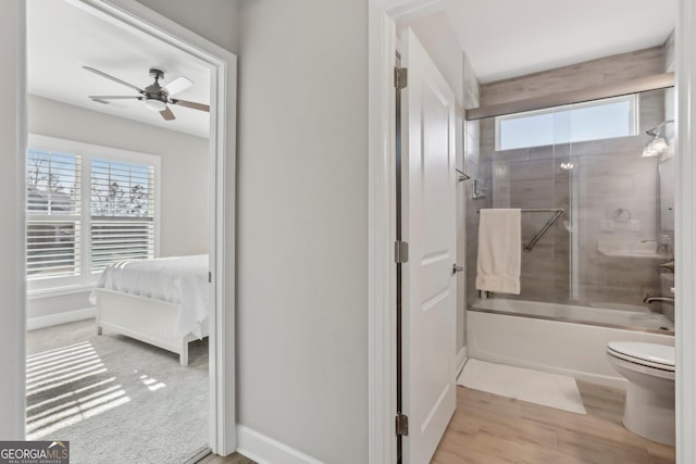 bathroom featuring hardwood / wood-style flooring, combined bath / shower with glass door, ceiling fan, and toilet