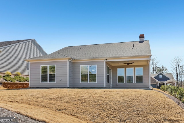 rear view of house featuring ceiling fan and a lawn